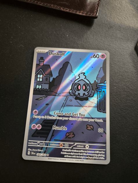 A Duskull Illustration Rare card photographed at an angle, with perspective distortion